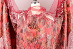 a close-up view of a red and gold patterned fabric, possibly a dress or garment, with intricate designs and embellishments.
