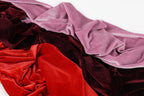 a close-up view of various colorful fabrics, including red velvet, burgundy velvet, and pink velvet, arranged in a visually appealing manner.