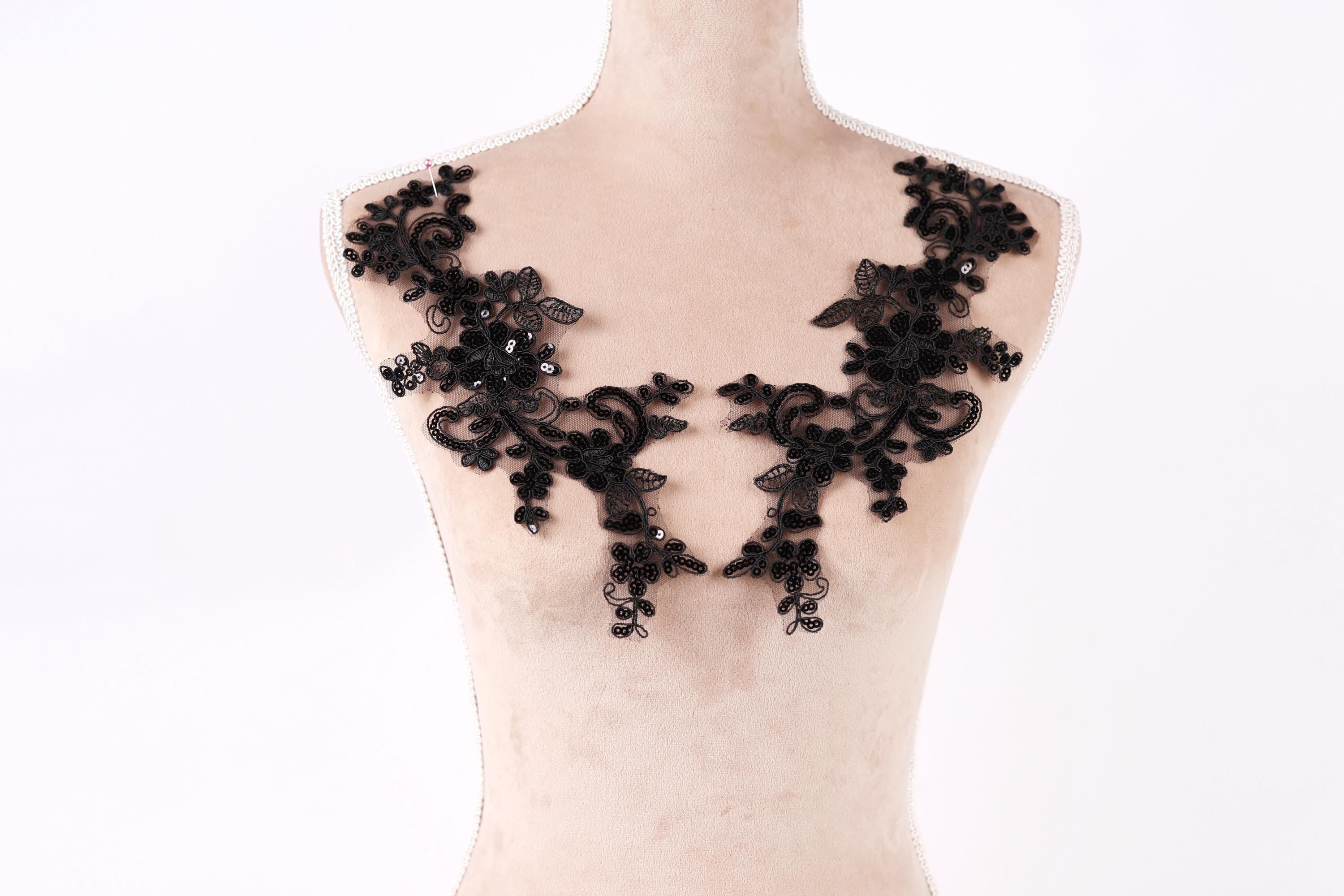 A mannequin wearing a black lace dress with intricate floral patterns.