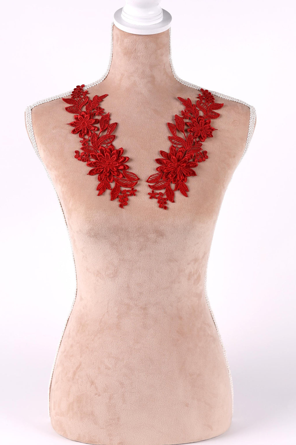 A mannequin wearing a red floral necklace with red flowers and leaves.