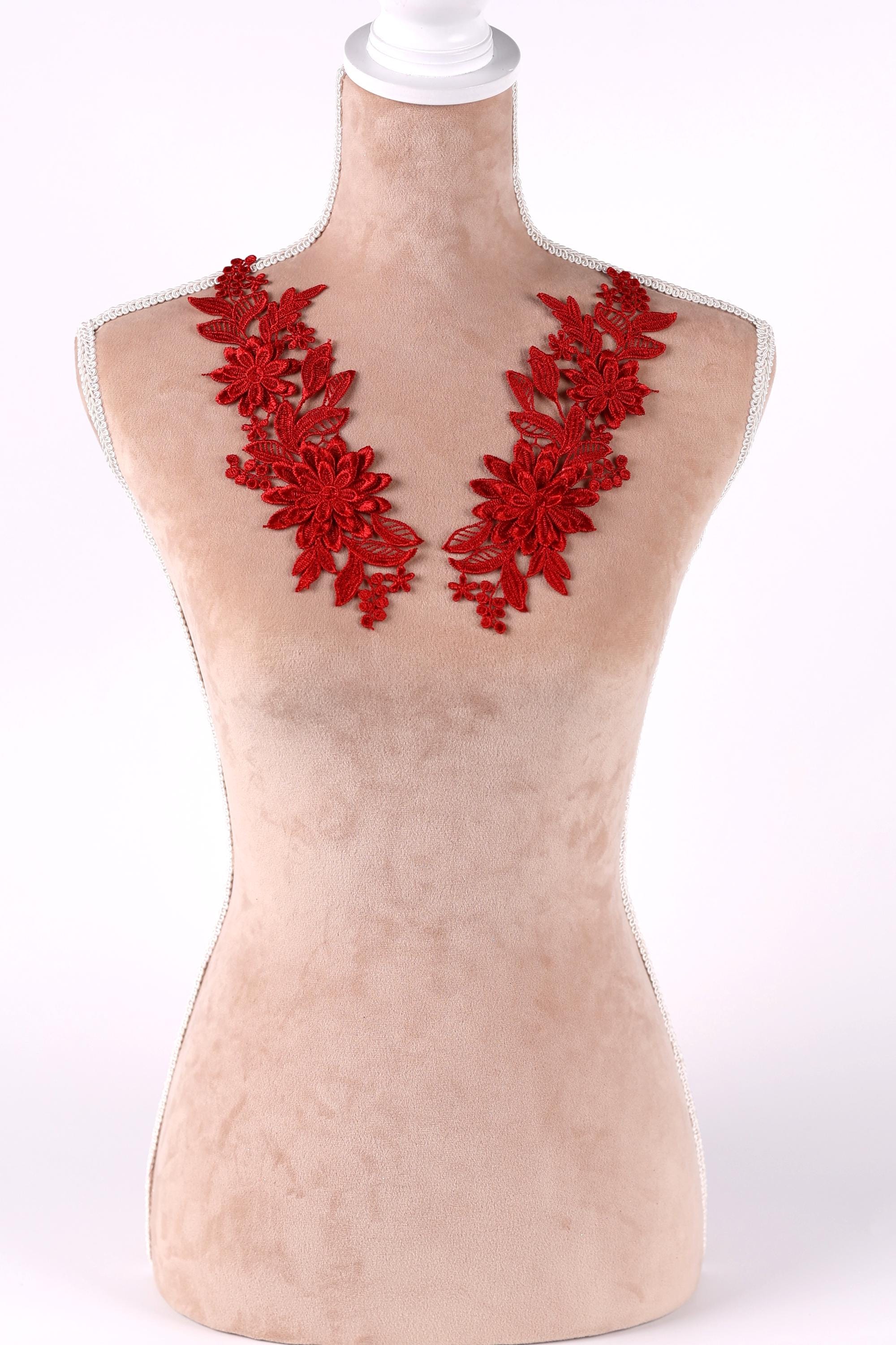 A mannequin wearing a red floral necklace with red flowers and leaves.