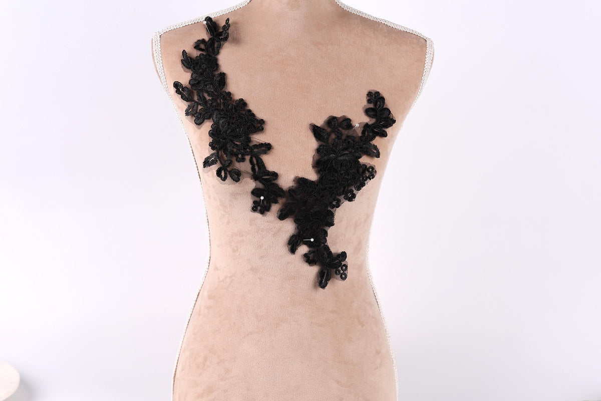 A mannequin with a black lace design on its bust, featuring a floral pattern.
