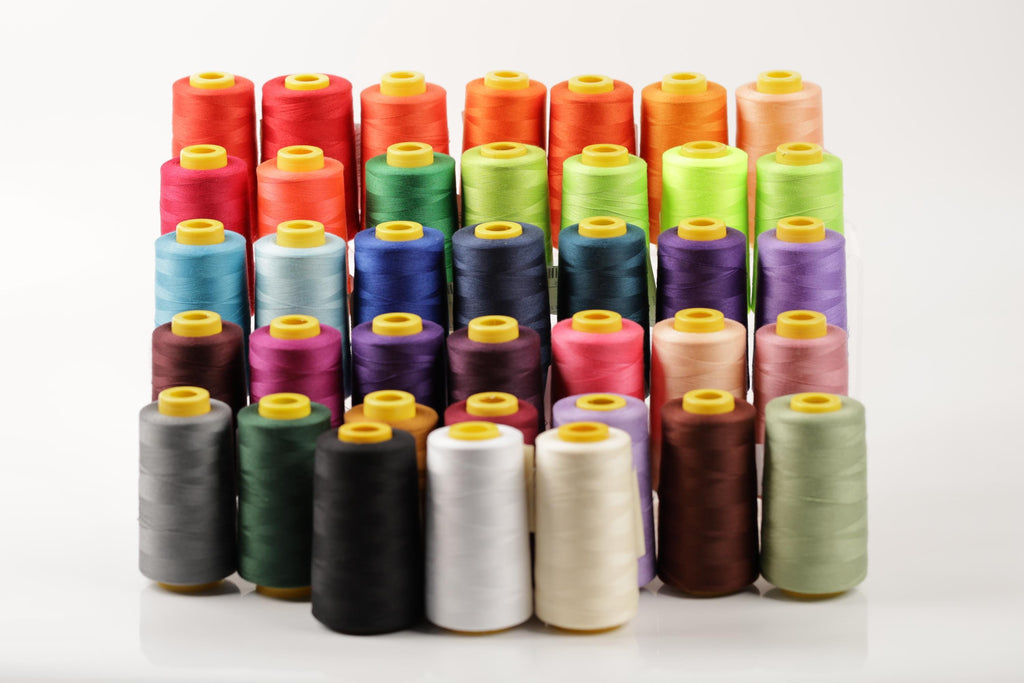A collection of colorful spools of thread arranged in rows on a white background.
