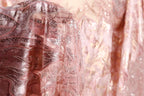A close-up view of a delicate, pink fabric with intricate beading and sequin details, creating a visually striking and elegant appearance.