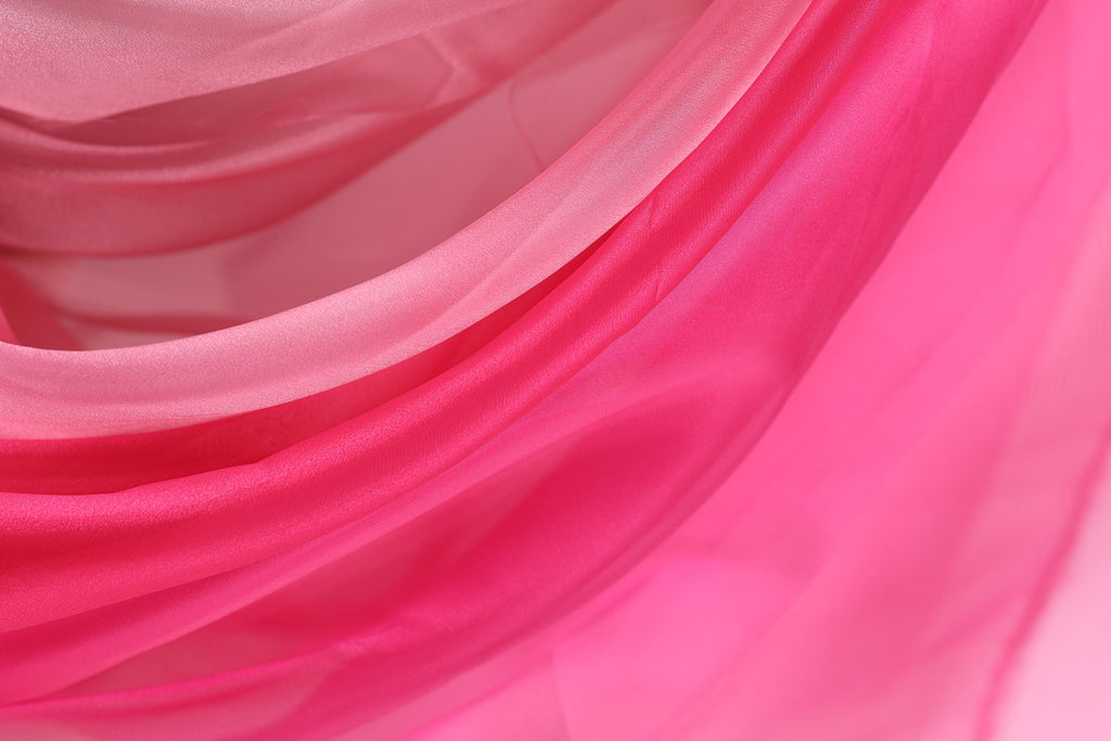 a close-up view of a fabric with a pink and white color scheme, featuring a soft, flowing texture.