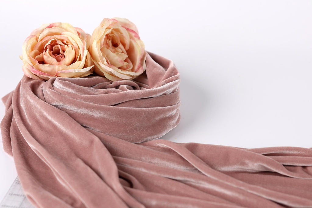 two pink roses resting on a pink velvet fabric.