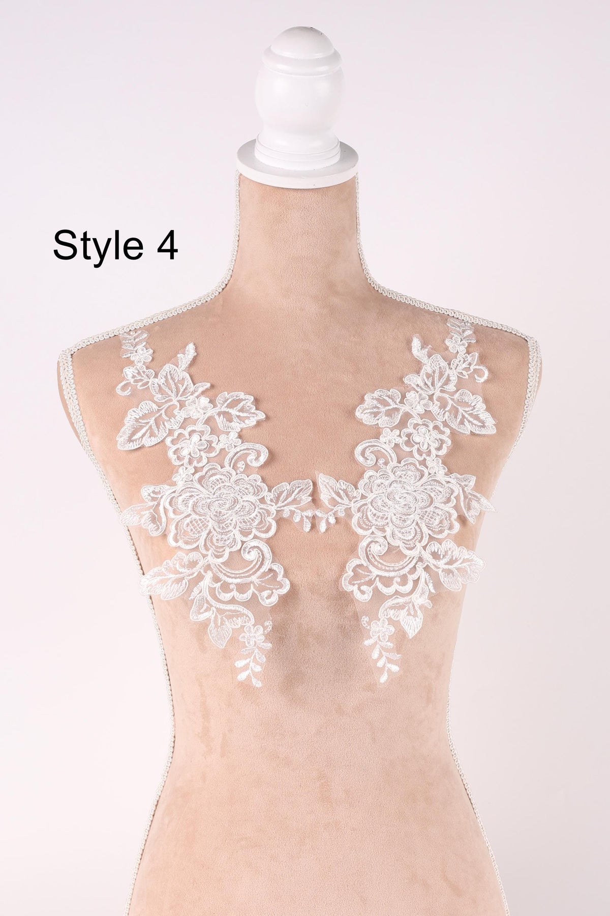 A mannequin wearing a white lace bodice with intricate floral patterns.