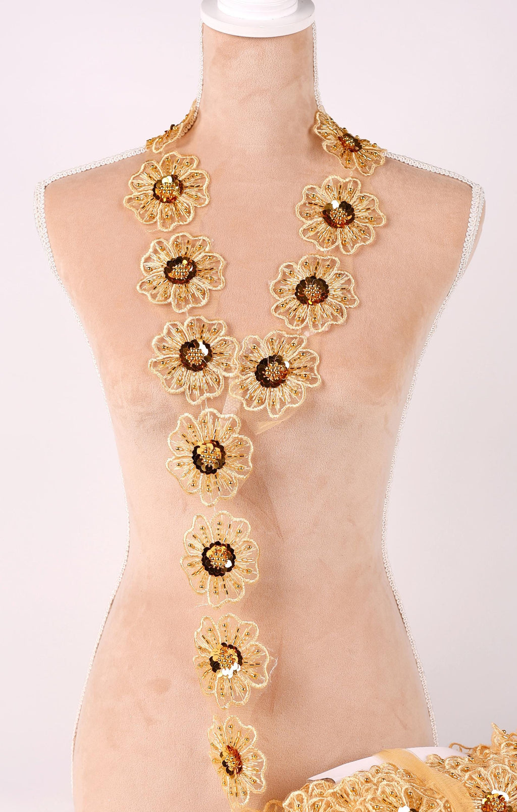 A mannequin wearing a gold necklace with numerous small, intricately designed flowers.