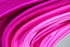 The image is a close-up of a fabric with a vibrant pink color, featuring a smooth, flowing texture.