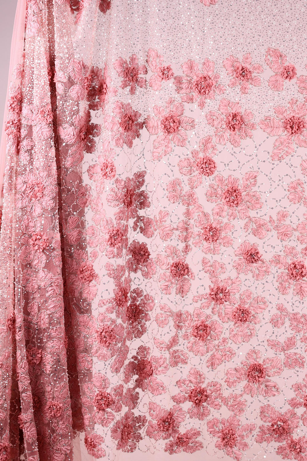a close-up view of a delicate, pink floral fabric with a repeating pattern of pink flowers on a light pink background.