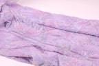 a close-up view of a fabric with a purple floral pattern, featuring small sequins or beads that add texture and sparkle to the fabric.
