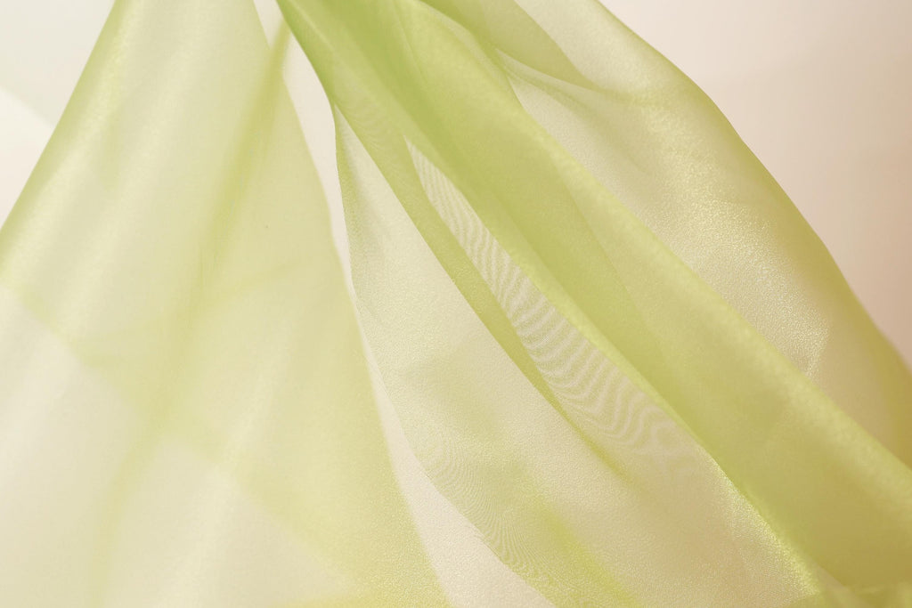 a close-up view of a piece of green fabric, possibly silk or chiffon, with a soft, flowing texture.