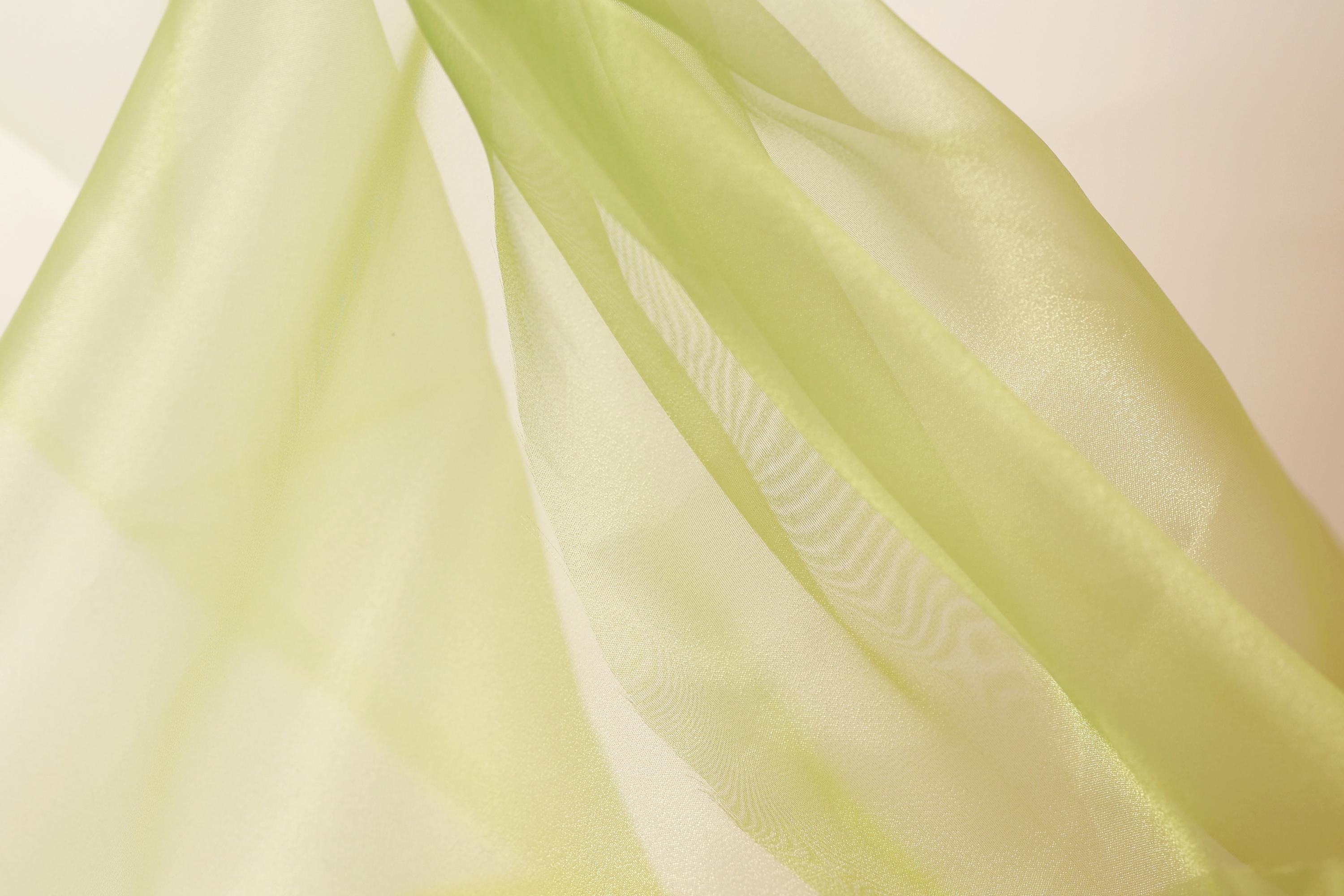 a close-up view of a piece of green fabric, possibly silk or chiffon, with a soft, flowing texture.
