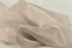 a close-up view of a soft, light-colored fabric, possibly silk or chiffon, with a slightly wrinkled texture.