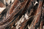 The image is a close-up of a fabric with a floral pattern, featuring a mix of brown, black, and gold colors. The fabric appears to be made of a shiny material, possibly sequin or lace, and has a textured, flowing appearance.