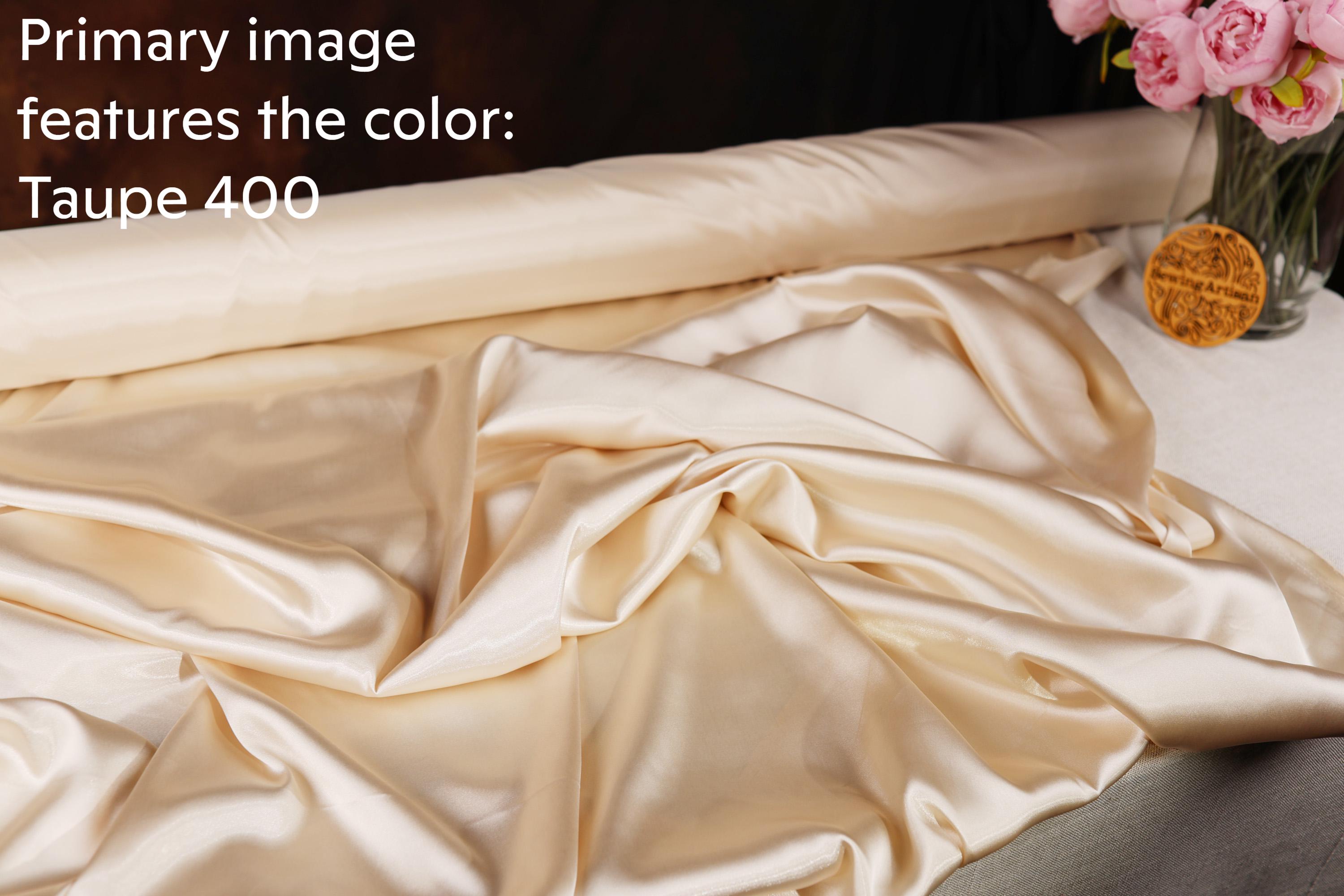 a roll of gauzy fabric, specifically Taupe 400, with a vase of pink flowers placed next to it.