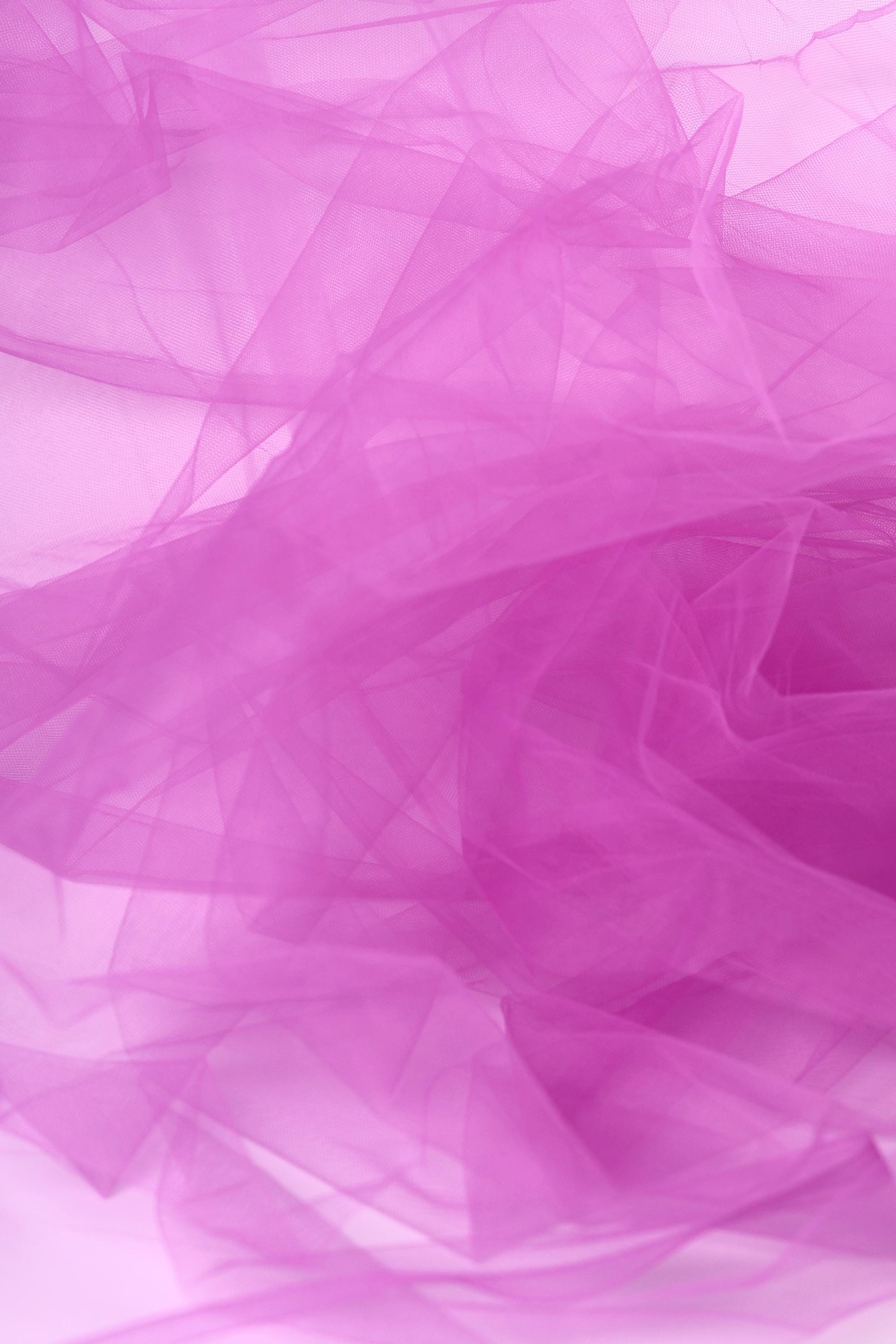 The image is a close-up of a soft, flowing fabric in a vibrant shade of pink. The fabric appears to be made of sheer material, giving it a delicate and ethereal appearance. The image does not contain any discernible objects or text, and the focus is solely on the fabric's texture and color.