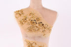 A mannequin with a beige fabric back, adorned with intricate gold embroidery in the shape of flowers and leaves.