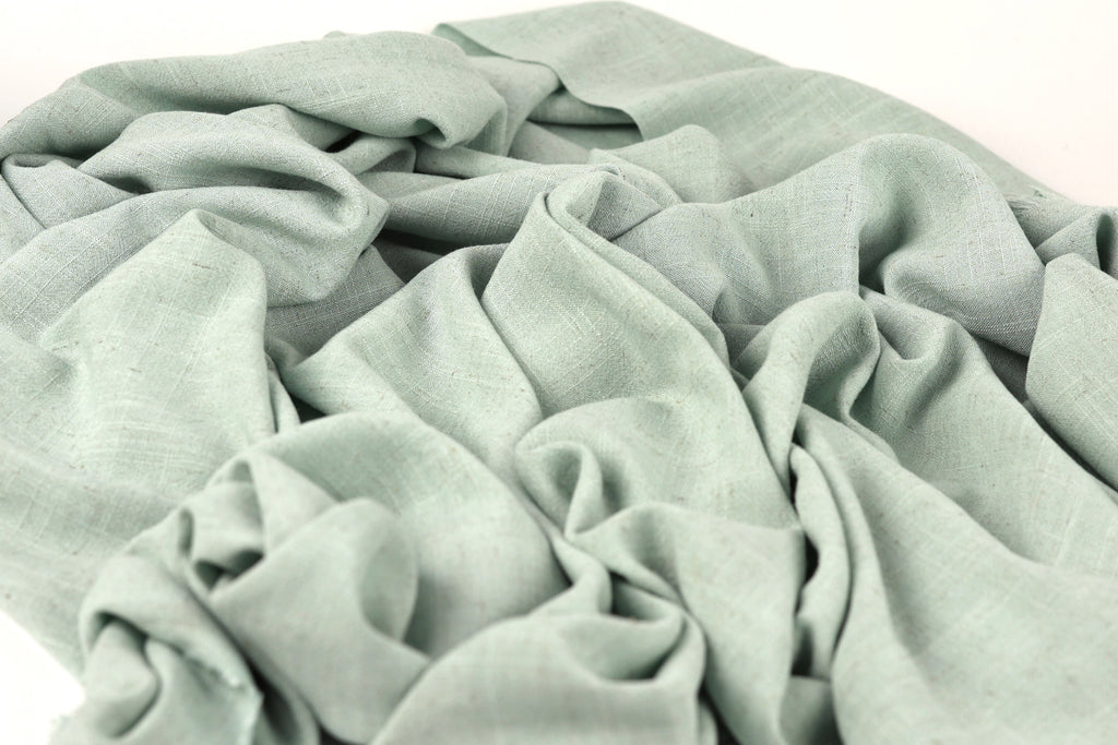 a close-up view of a crumpled, light green fabric, possibly a piece of clothing or textile.