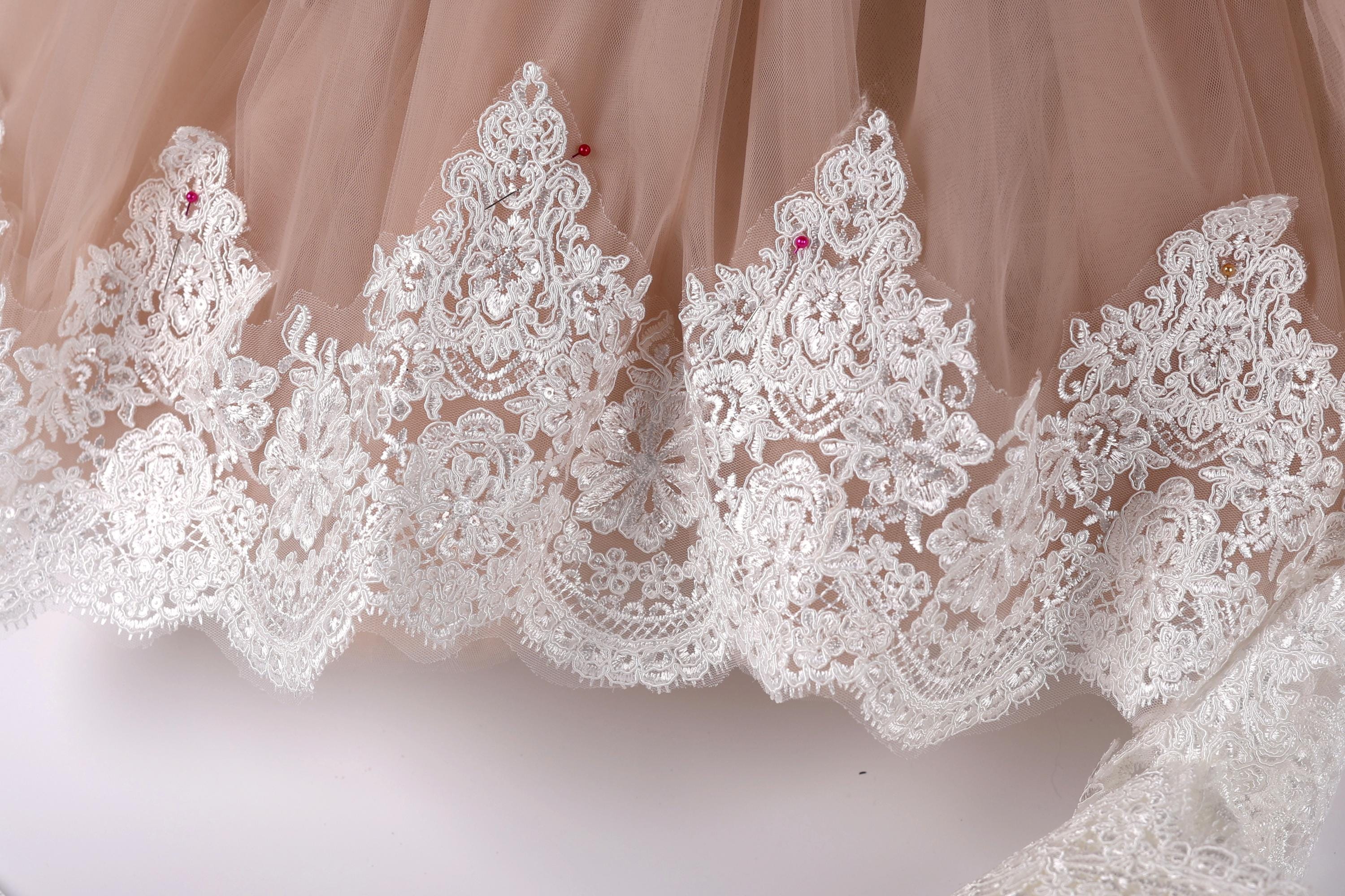 A close-up view of a delicate, lace-trimmed skirt or dress, with intricate patterns and designs.