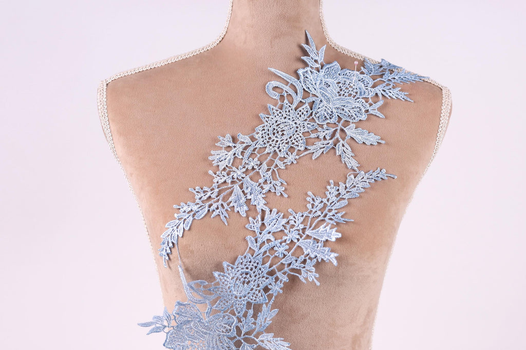 A mannequin torso with a delicate, intricate blue lace pattern covering the back.