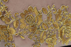a close-up view of a delicate, intricate gold embroidered design on a fabric surface.