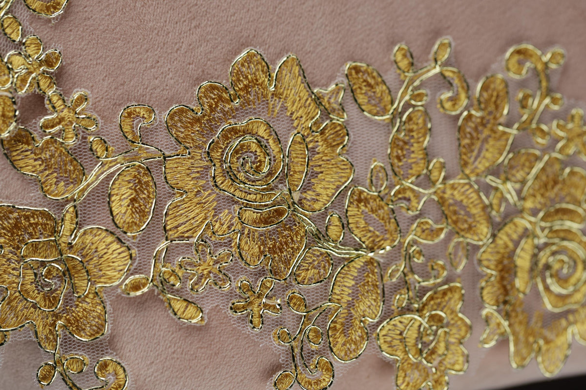 a close-up view of a delicate, intricate gold embroidered design on a fabric surface.