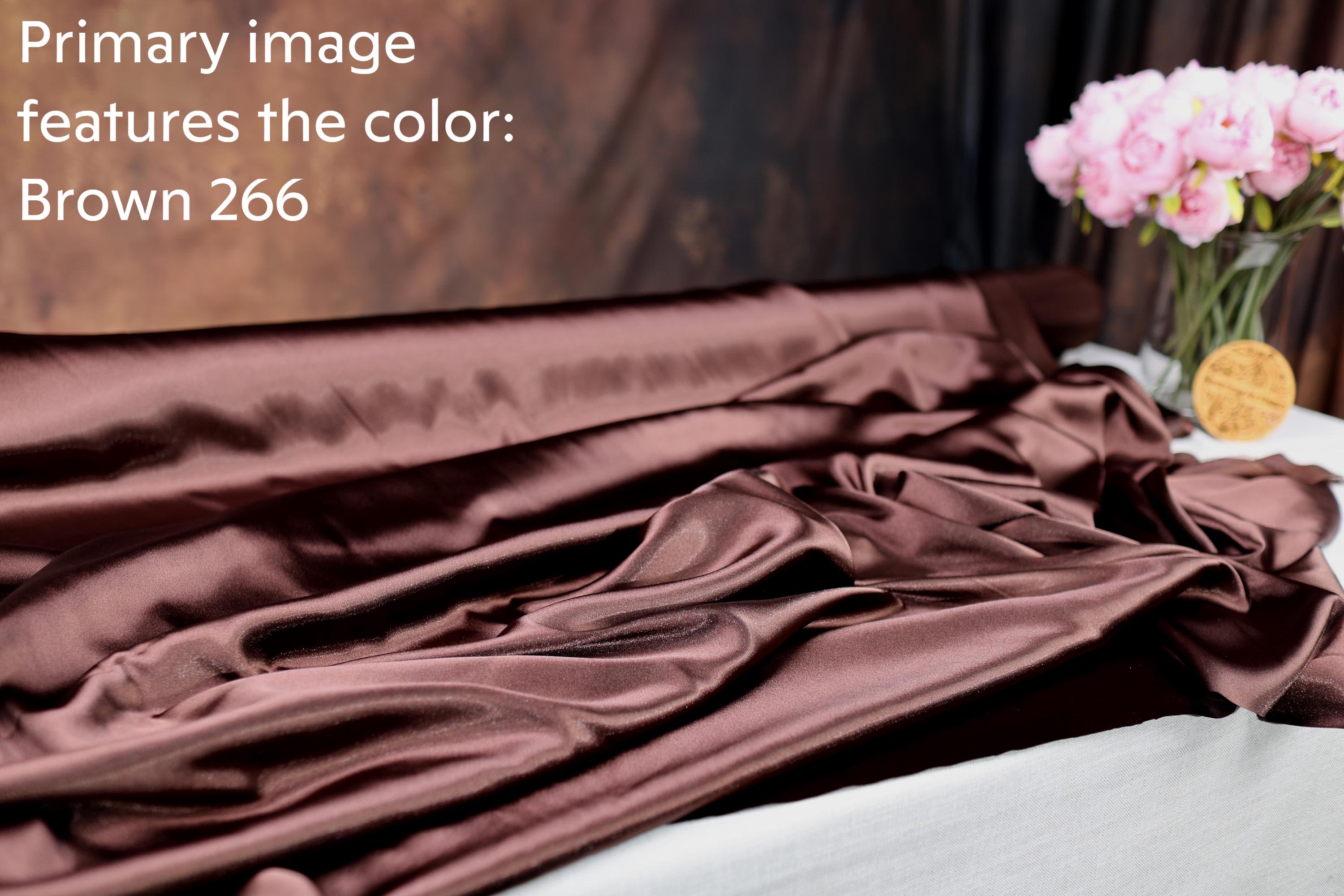 a brown fabric with a floral pattern, and there is a vase of pink flowers on a table next to it.