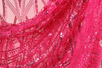The image is a close-up of a vibrant pink fabric with a pattern of sequins and beads, creating a visually striking and eye-catching design.
