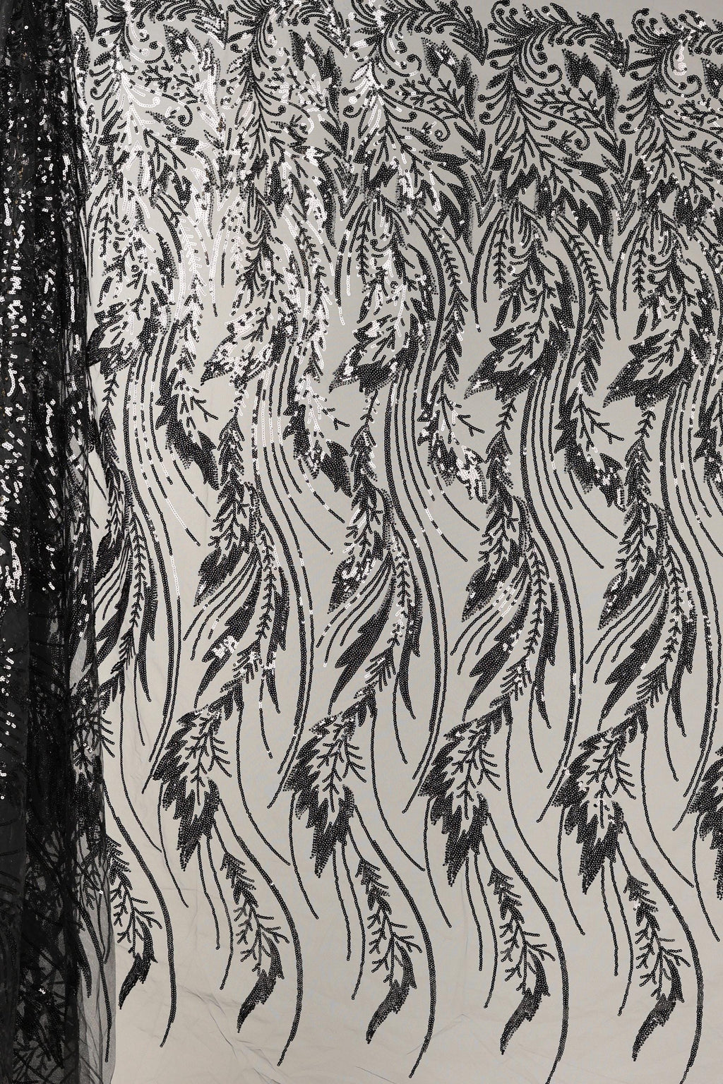 a close-up view of a fabric with a repeating pattern of black and white lines and shapes, resembling a floral or leaf-like design. The pattern appears to be intricate and detailed, with the lines and shapes varying in size and orientation, creating a visually striking and dynamic composition.