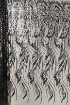 a close-up view of a fabric with a repeating pattern of black and white lines and shapes, resembling a floral or leaf-like design. The pattern appears to be intricate and detailed, with the lines and shapes varying in size and orientation, creating a visually striking and dynamic composition.