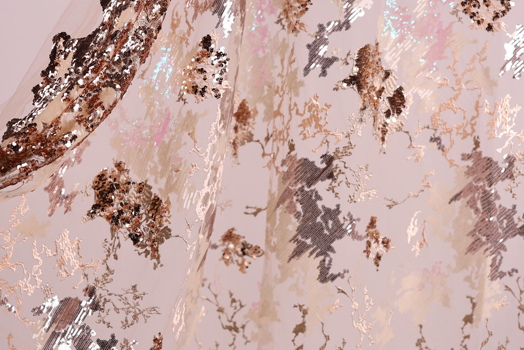 The image is a close-up of a fabric with a metallic, sequined pattern in shades of pink, brown, and gold. The fabric appears to be a sheer or sheer-like material, with a textured and shiny appearance.