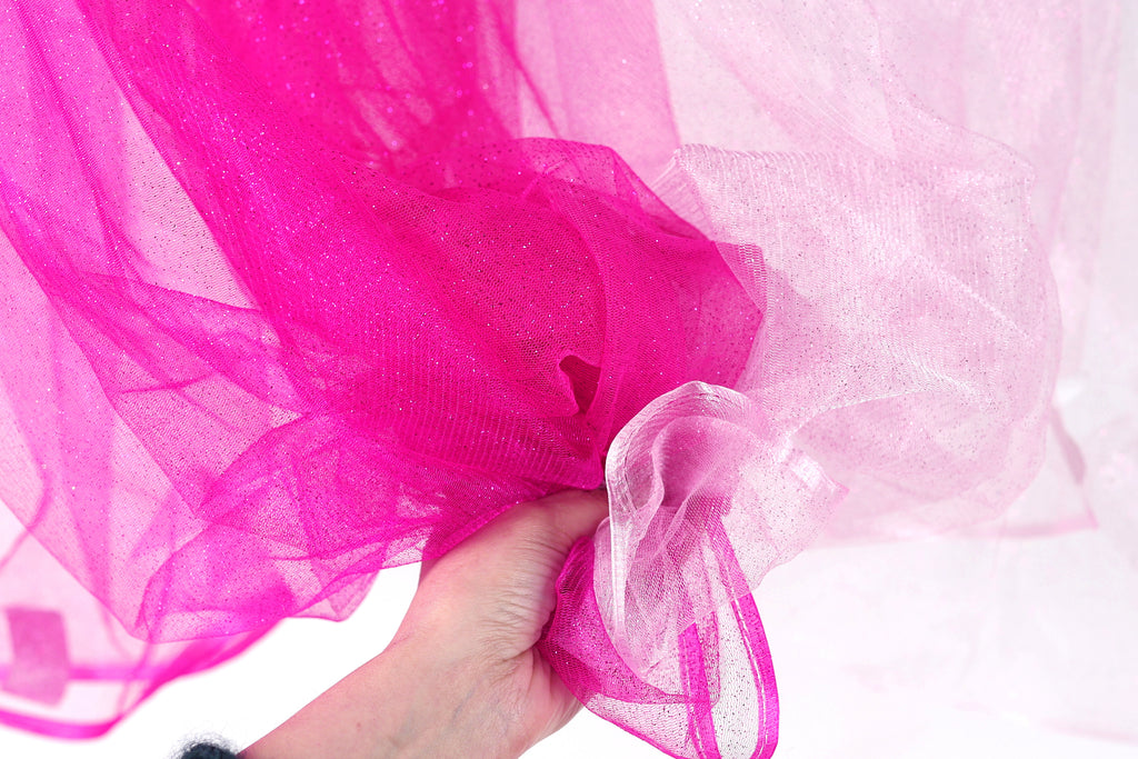 A hand is holding a piece of pink and white fabric, with the fabric appearing to be made of sheer material.