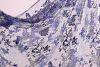 The image is a close-up view of a fabric with a floral pattern in shades of purple and blue. The fabric appears to be made of sequins or other decorative materials, creating a visually striking and intricate design.