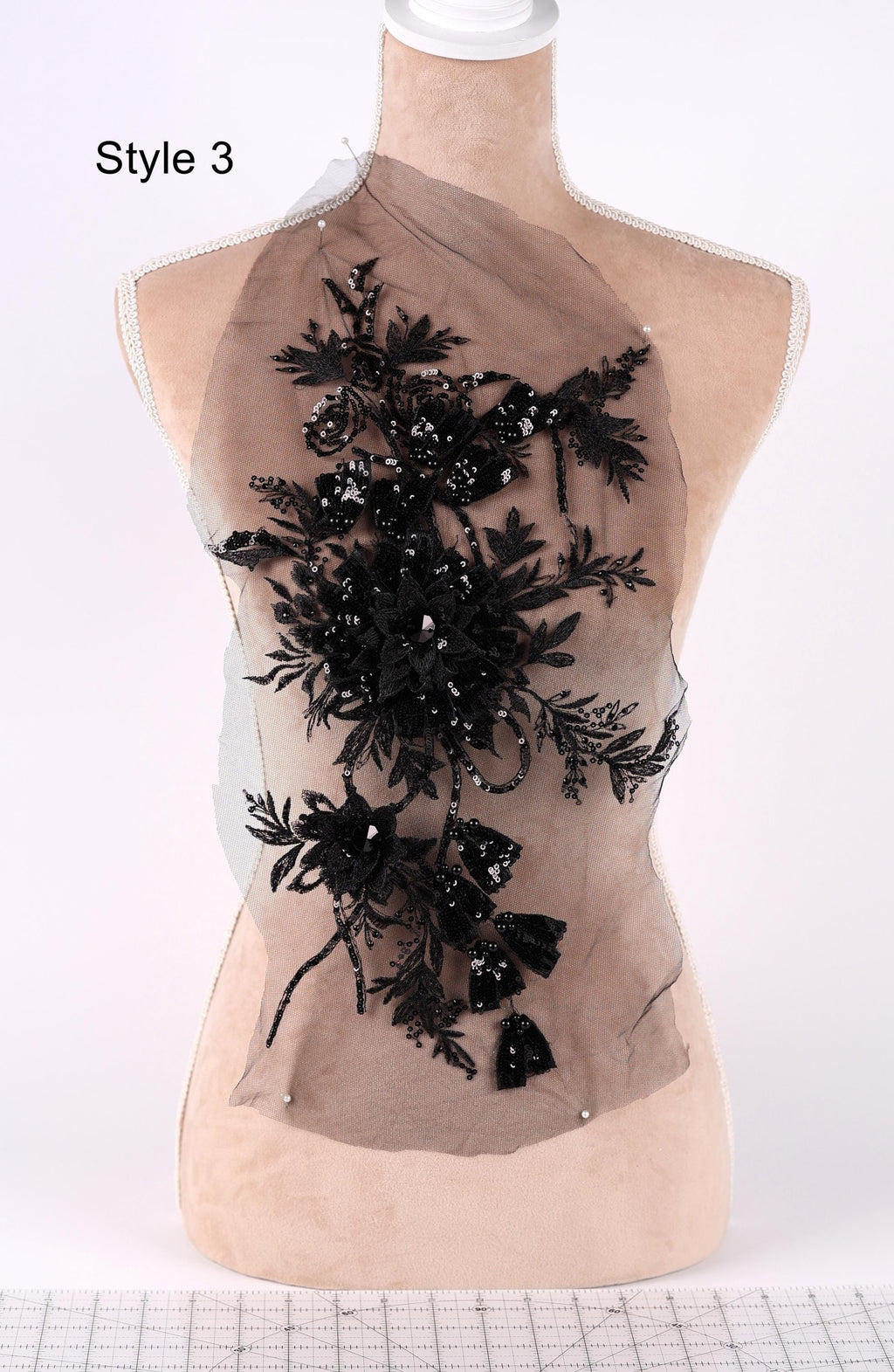 A mannequin with a decorative black floral pattern on its bust area, displayed on a mannequin stand.