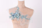 A mannequin with a delicate, floral-designed fabric draped over its shoulder.