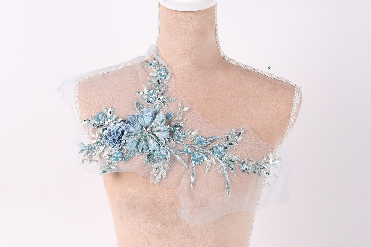 A mannequin with a delicate, floral-designed fabric draped over its shoulder.