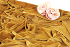 a close-up view of a crumpled, golden fabric with two delicate pink roses resting on top of it.