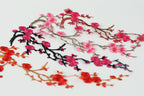 a variety of pink and red floral branches, including cherry blossoms and red flowers, arranged in a visually appealing manner.