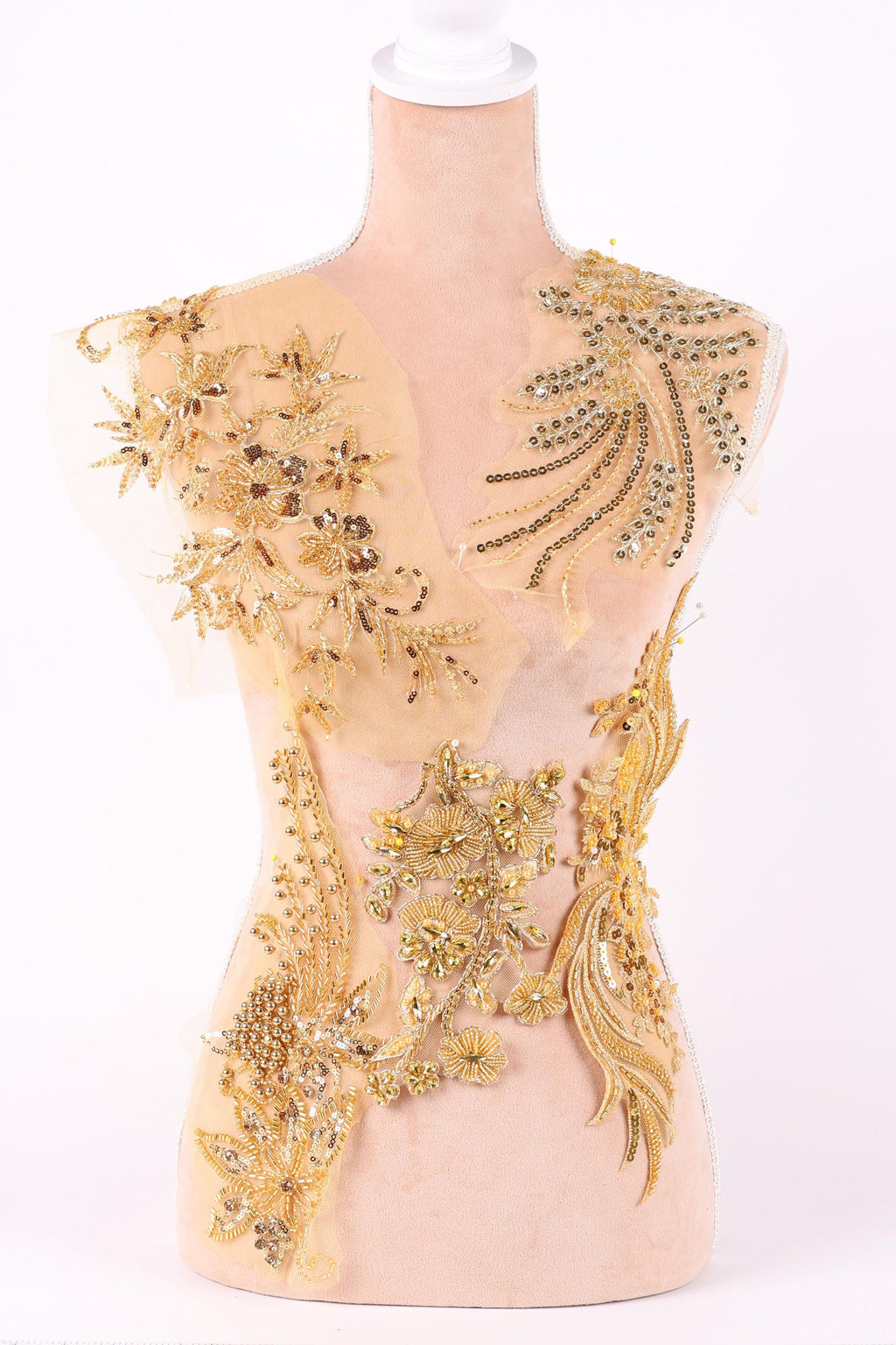 a mannequin with a beige dress adorned with intricate gold embroidery and beading.