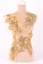 a mannequin with a beige dress adorned with intricate gold embroidery and beading.