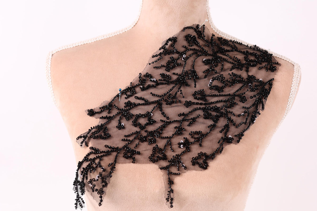 A mannequin wearing a black lace dress with a floral pattern.