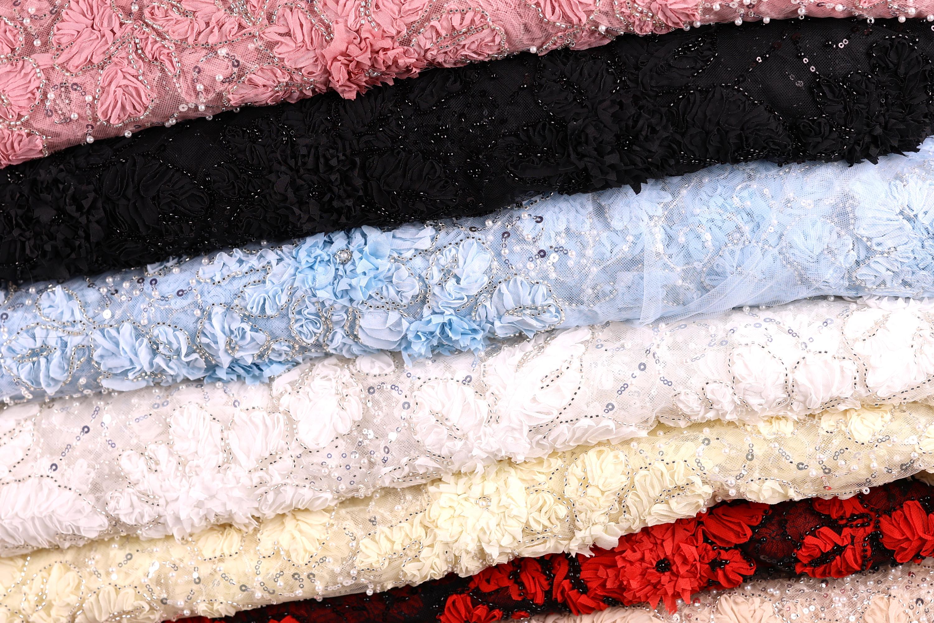A close-up image of various colorful fabric swatches, including pink, black, blue, white, and red, arranged in a layered fashion.