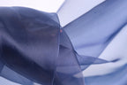 The image is a close-up of a blue fabric, possibly silk or chiffon, with a blurred background.