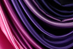 a close-up view of a fabric with a gradient of colors, transitioning from a deep purple to a lighter shade of purple. The fabric appears to be made of satin or a similar smooth, shiny material.
