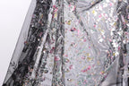 a close-up view of a delicate, intricately embroidered fabric with a floral pattern. The fabric appears to be a sheer material, with a black background that contrasts with the colorful floral design. The image is not a single, continuous scene but rather a close-up of a section of the fabric, showcasing the detailed embroidery and the intricate design.