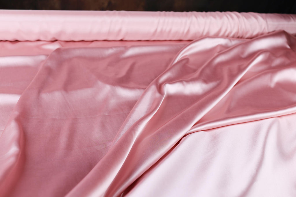 a close up of a pink sheet on a bed
