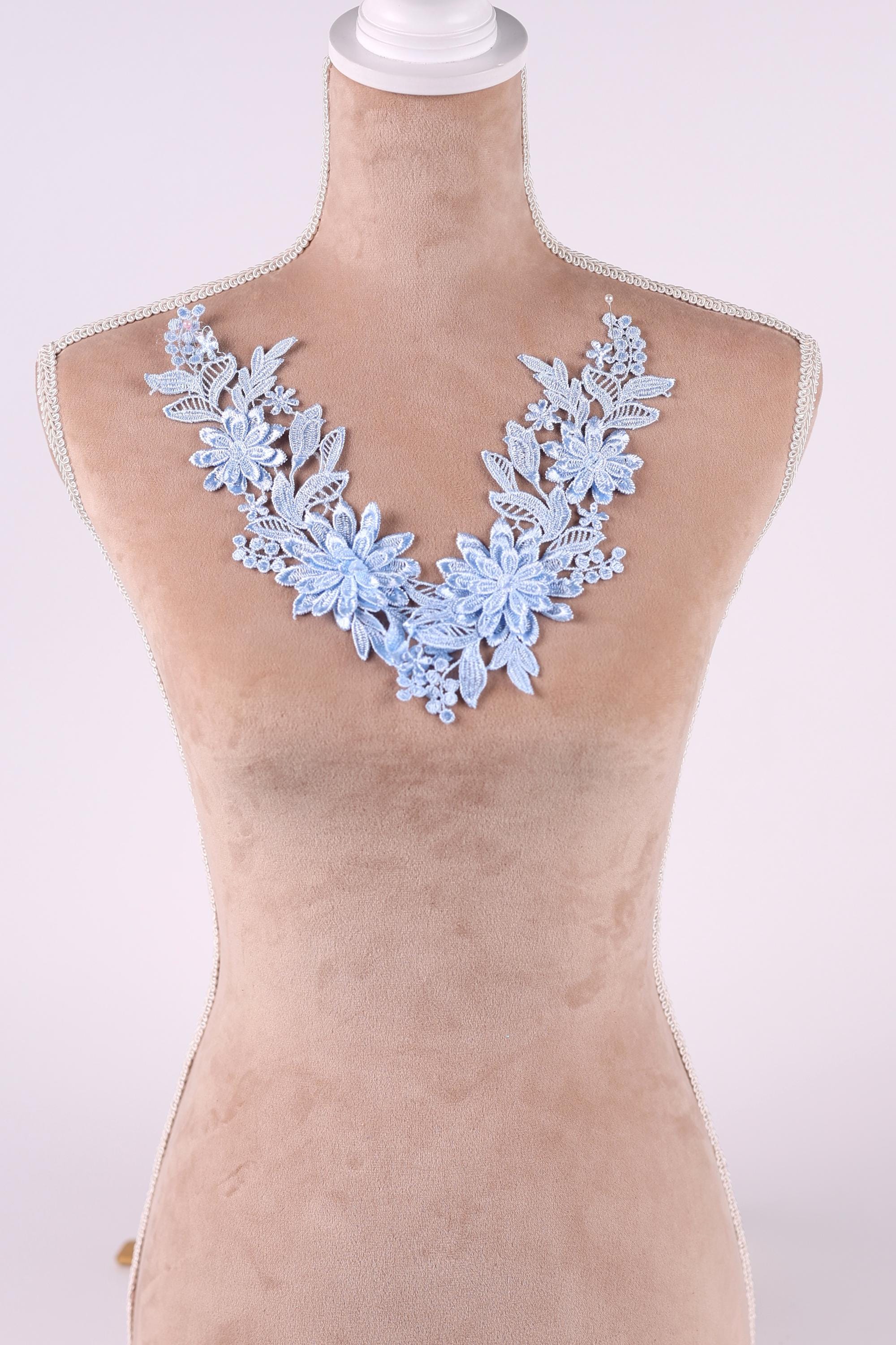 A mannequin wearing a light blue floral necklace with delicate blue flowers.