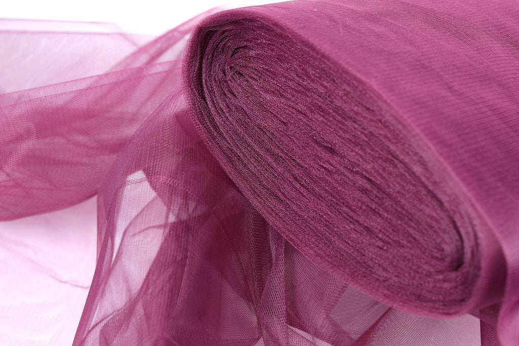 A close-up view of a roll of pink tulle fabric, with its soft and flowing texture visible.