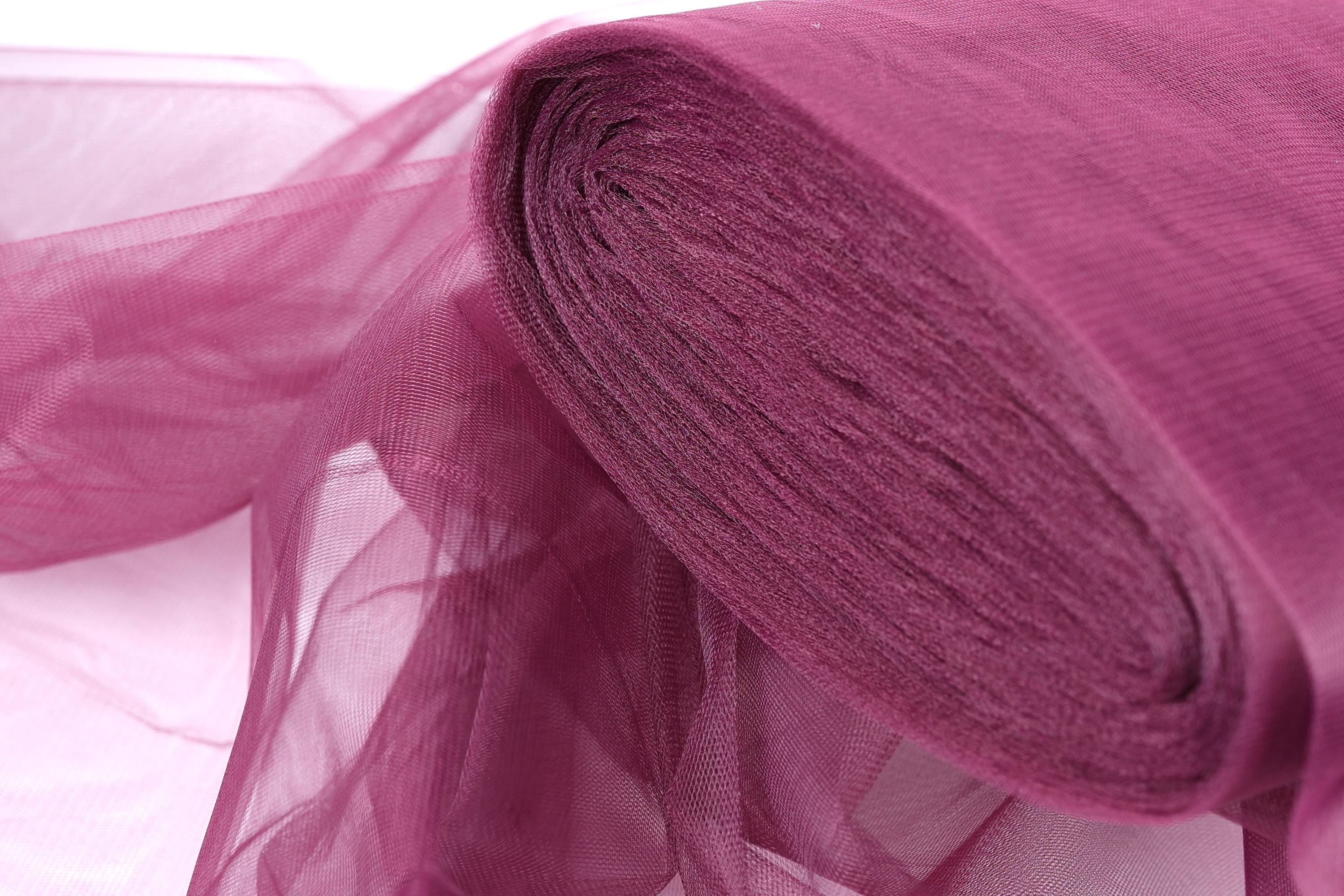 A close-up view of a roll of pink tulle fabric, with its soft and flowing texture visible.
